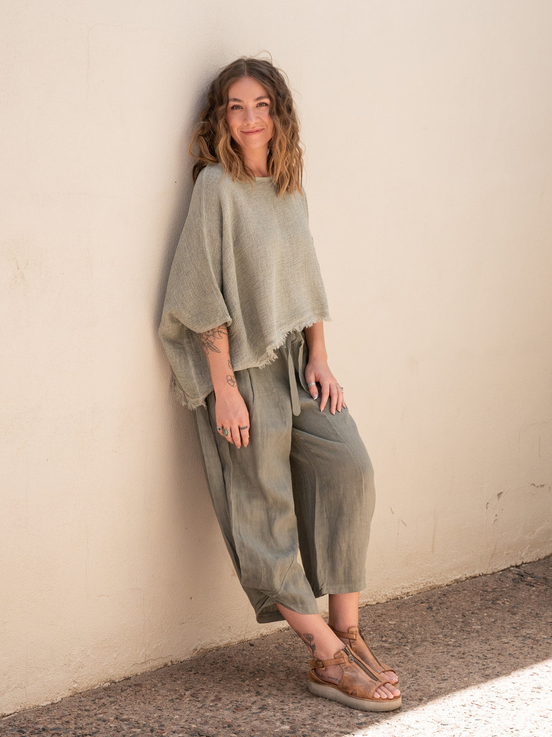Conscious Coterie Bondi Linen Top in Olive on model smiling leaning against wall