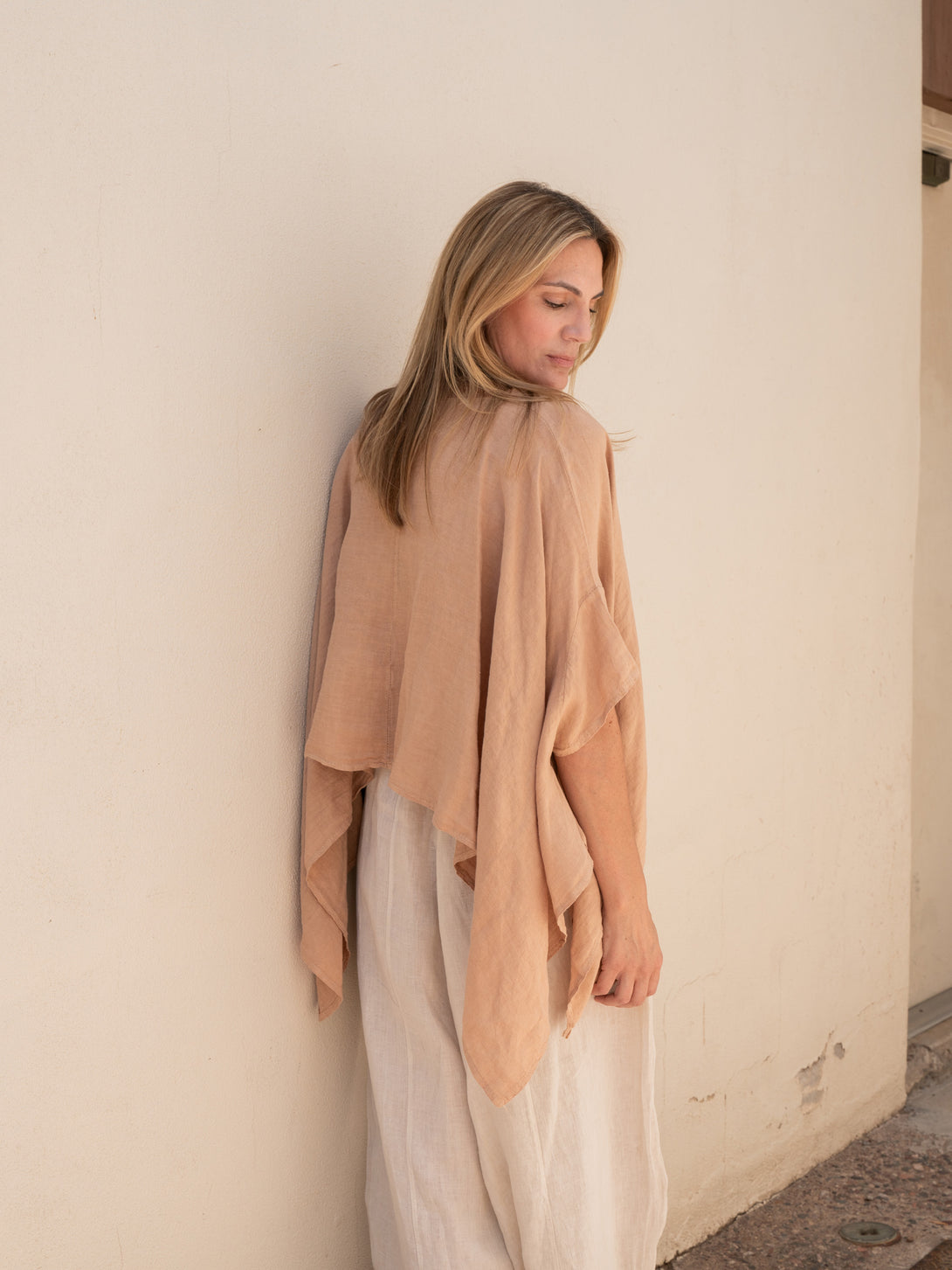 Conscious Coterie Brynn Linen Top in camel on model wearing beige pants standing against a wall