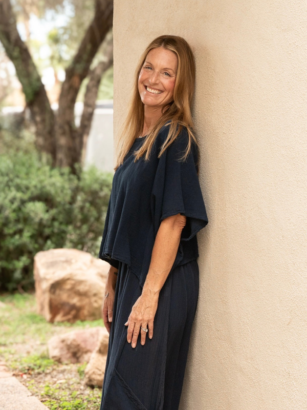 Conscious Coterie Carly top in navy blue model leaning against the wall showing side view of the top