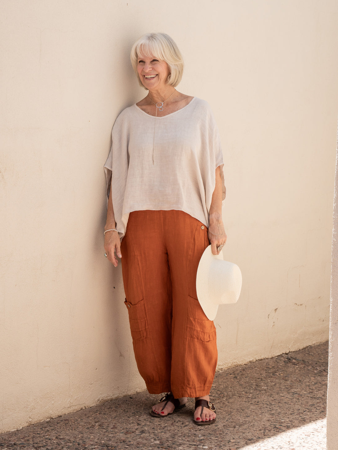 Conscious Coterie Holly Linen Pant in rust on model smiling full front view