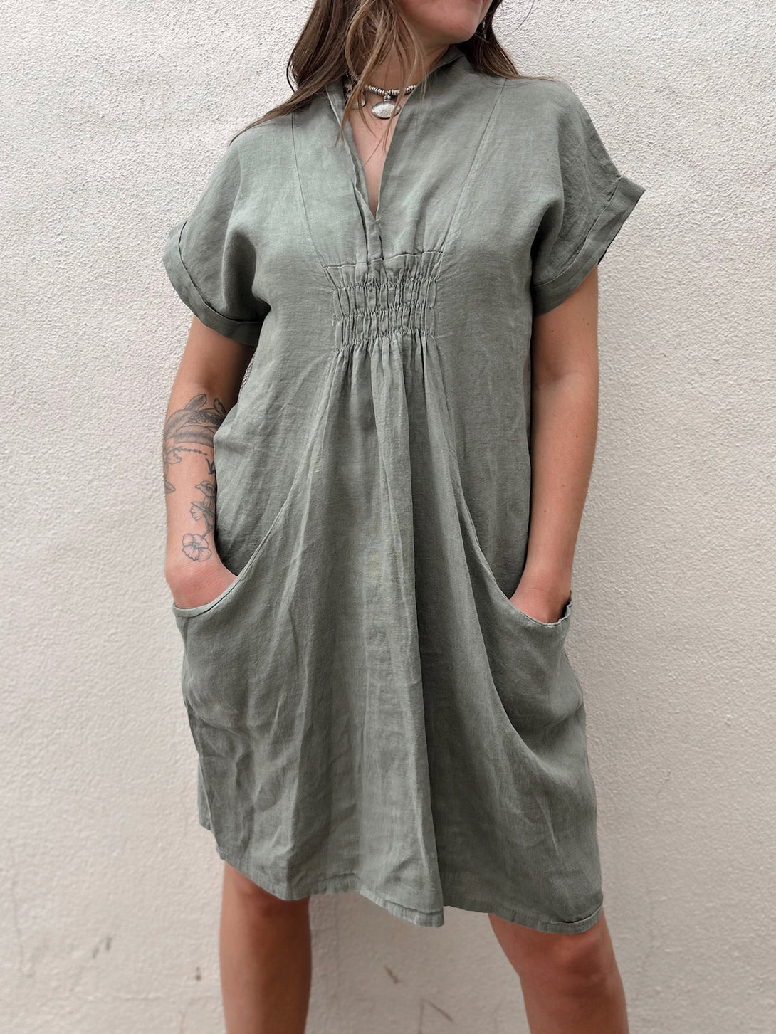 Conscious Coterie Kimmie Dress in Olive on model with hands in pockets front view