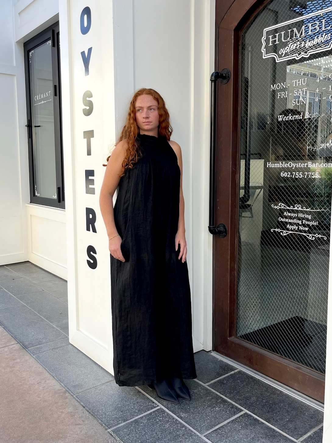 Conscious Coterie Kristen Jumpsuit in black front view of jumpsuit on woman leaning against the wall