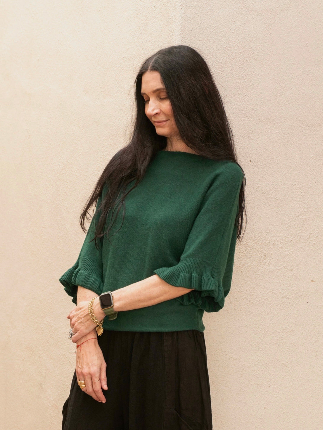Conscious Coterie Lila Ruffle Sleeve Sweater in forest green on model crossing arms side view