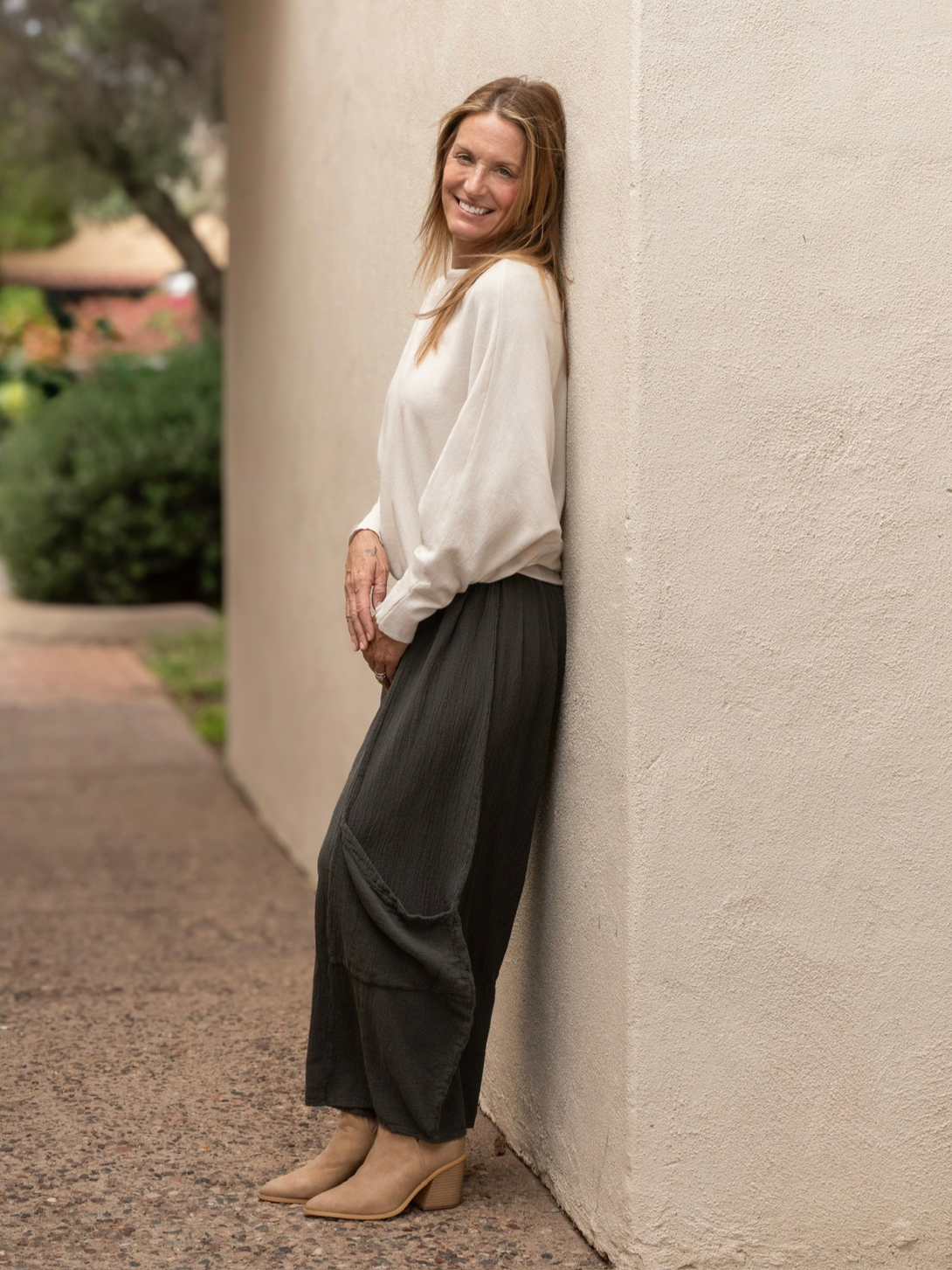 Conscious Coterie Lucy pant in charcoal grey full  body photo of woman wearing pants leaning on the wall
