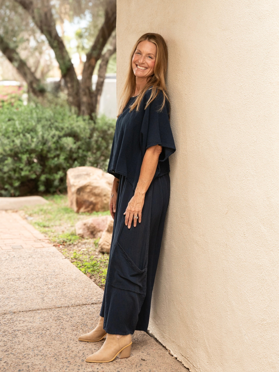 Conscious Coterie Lucy pant in navy blue full body view of the model leaning against the wall showing the side view of the pants