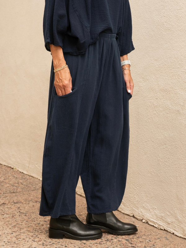 Conscious Coterie Mickey pant in navy blue close up photo of woman wearing barrel cut pants with hands in pant pockets