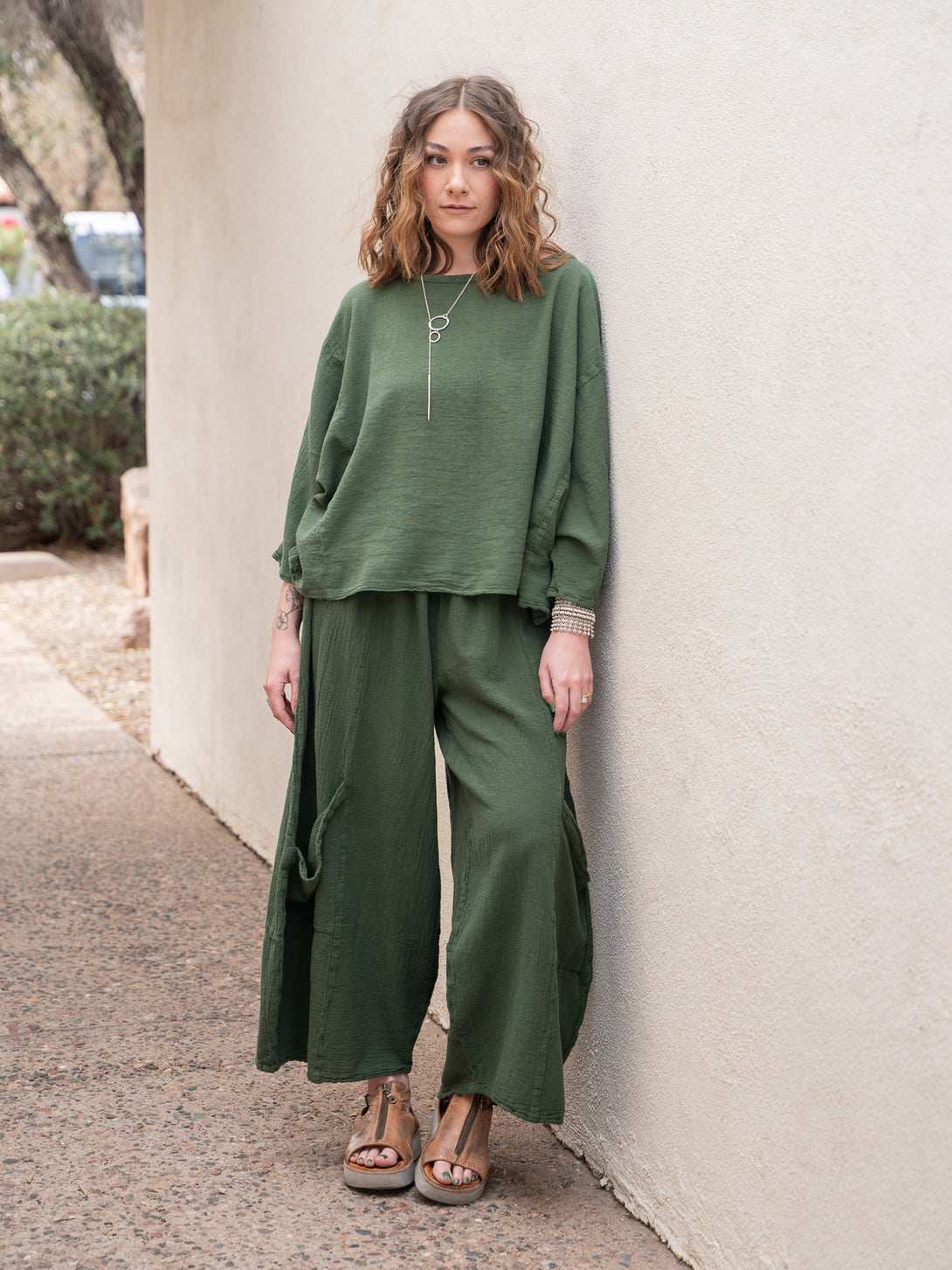 Conscious Coterie Rosie Top in moss cotton on model leaning against wall full front view