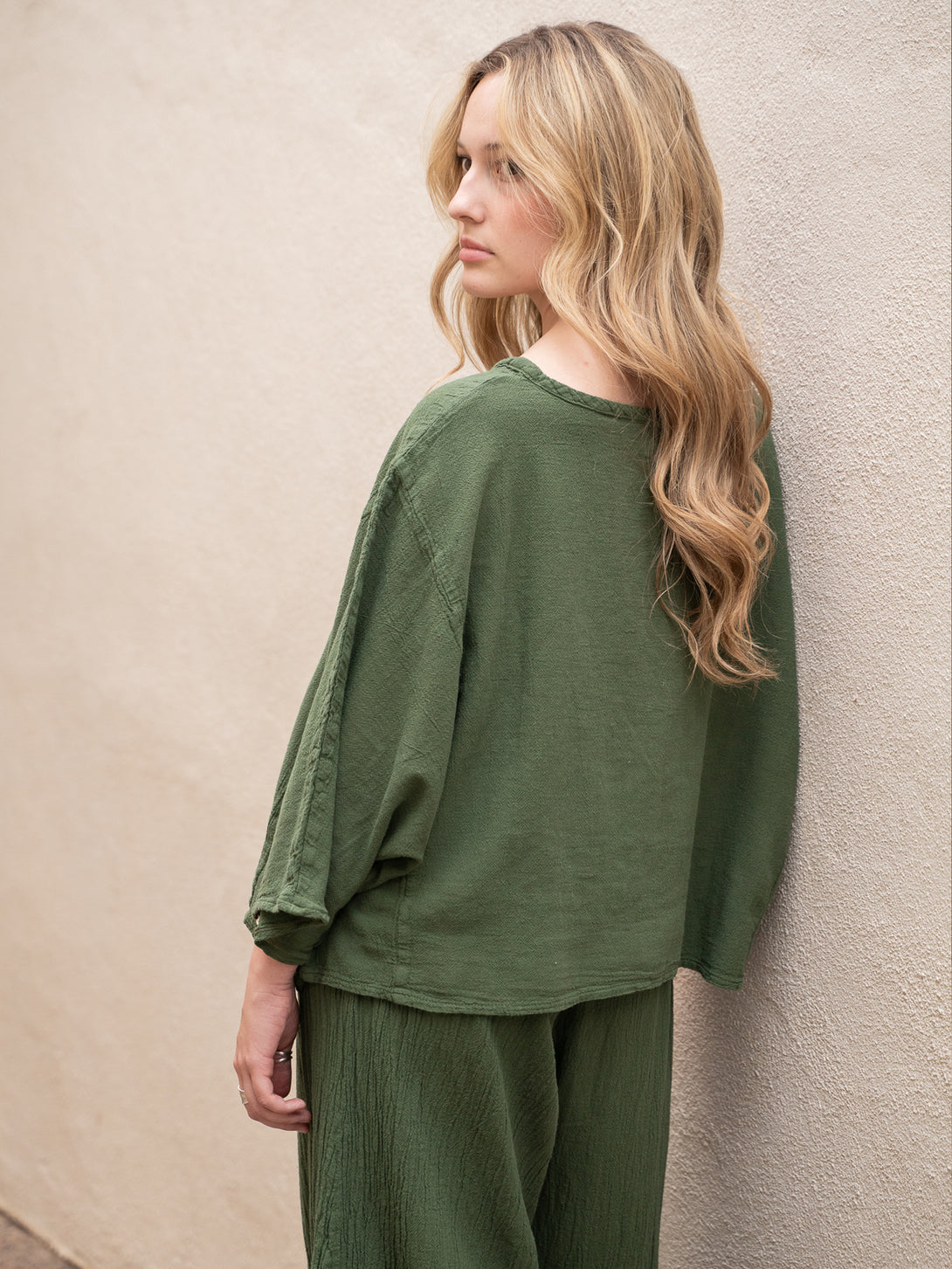 Conscious Coterie Rosie Top in moss cotton on model looking over shoulder back view