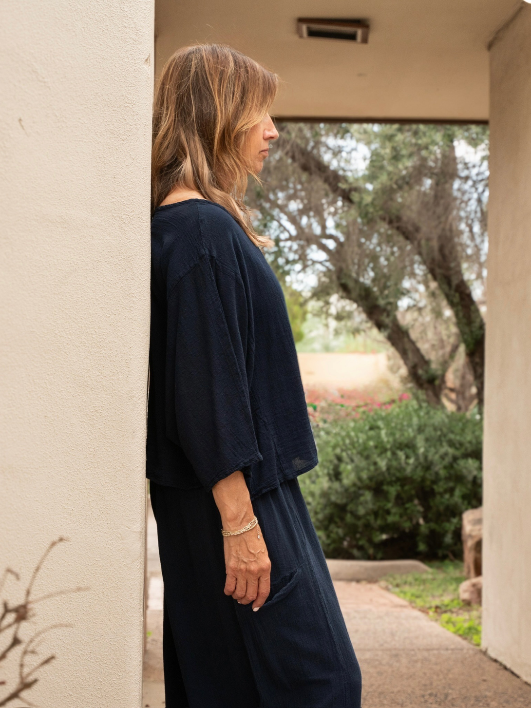 Conscious Coterie Rosie top in navy blue model showing side view of top leaning against a wall