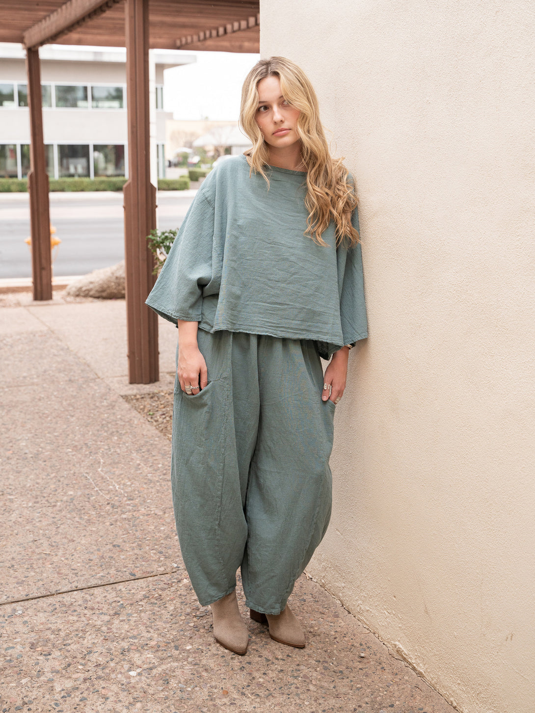 Conscious Coterie Rosie Top in sea cotton on model leaning against wall full front view