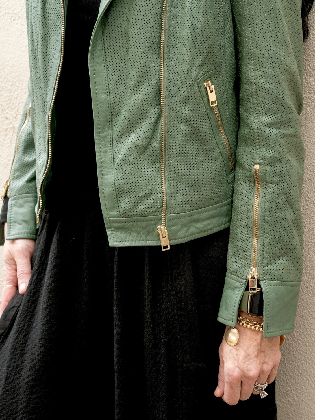 Conscious Coterie Sinta leather jacket in sage green close up image of details on the leather jacket showing gold zippers and perforated fabric