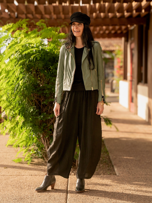 Conscious Coterie Sinta leather jacket in sage green fully body image of woman laughing wearing jacket unzipped 