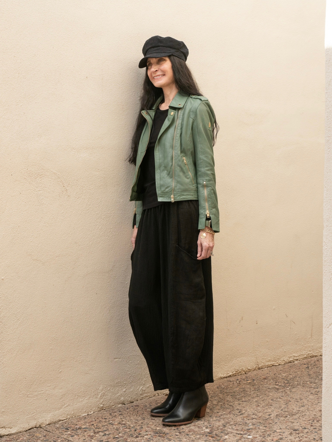 Conscious Coterie Sinta leather jacket in sage green full body image of woman wearing jacket showing side angle of jacket