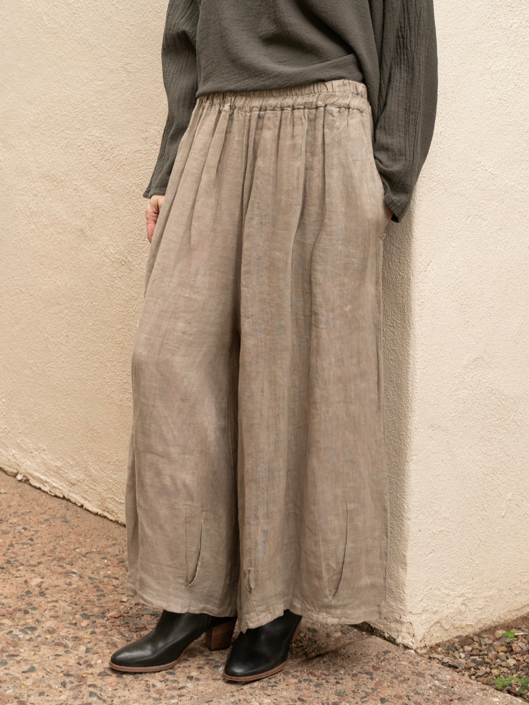 Conscious Coterie Stevie linen pant in taupe front view of pants on a woman leaning on a wall