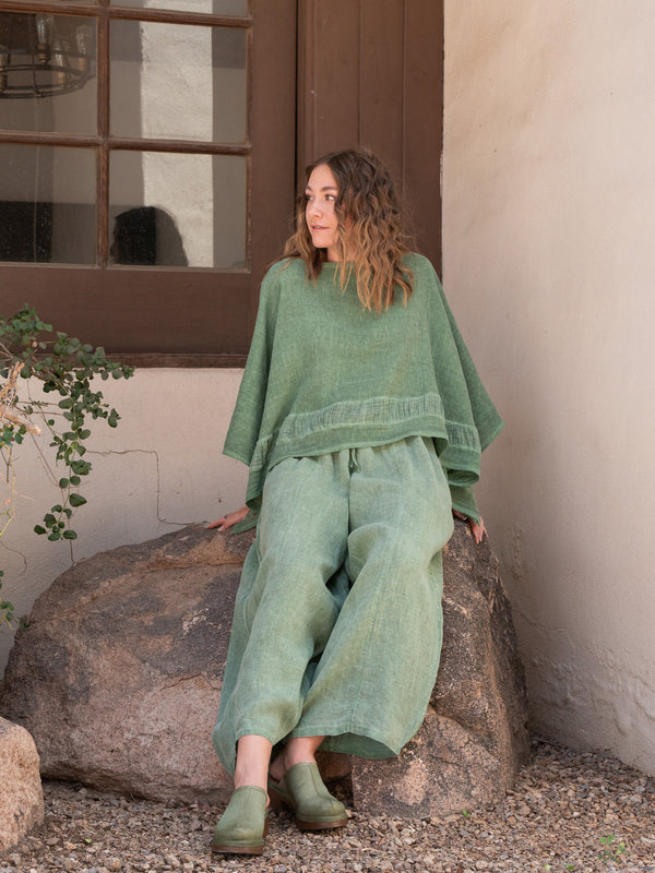 Conscious Coterie Tori Linen Top in Forest Green on model sitting on rock front view