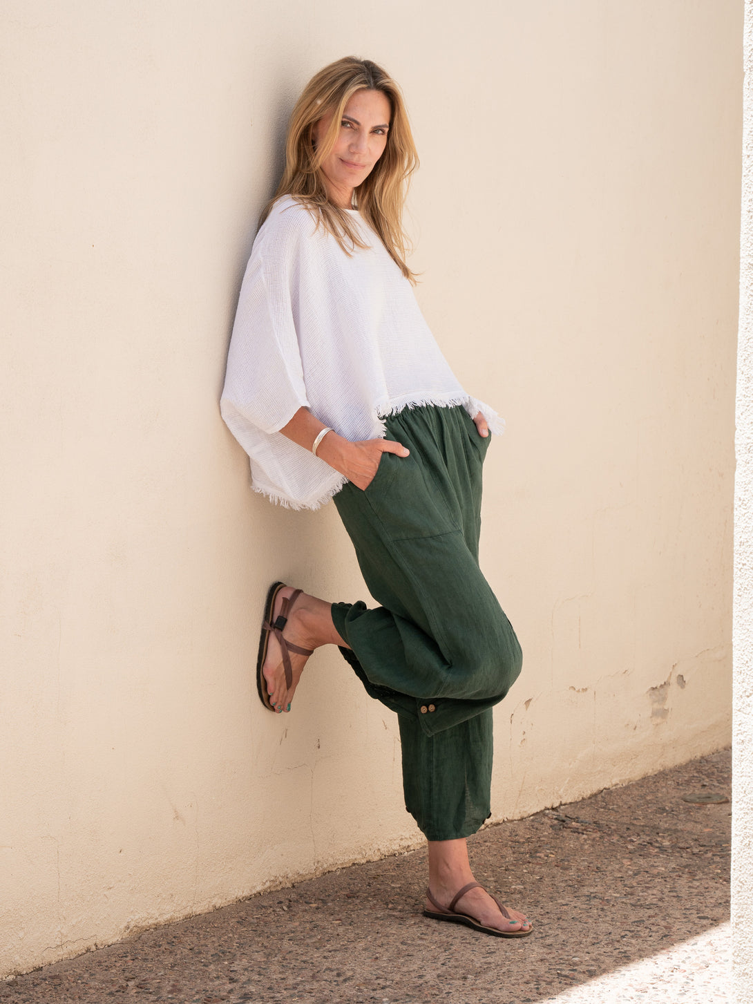 Conscious Coterie Yoli Linen Pant in Forest Green on model leaning against wall full front view