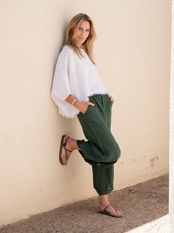 Conscious Coterie Yoli Linen Pant in Forest Green on model leaning against wall full front view