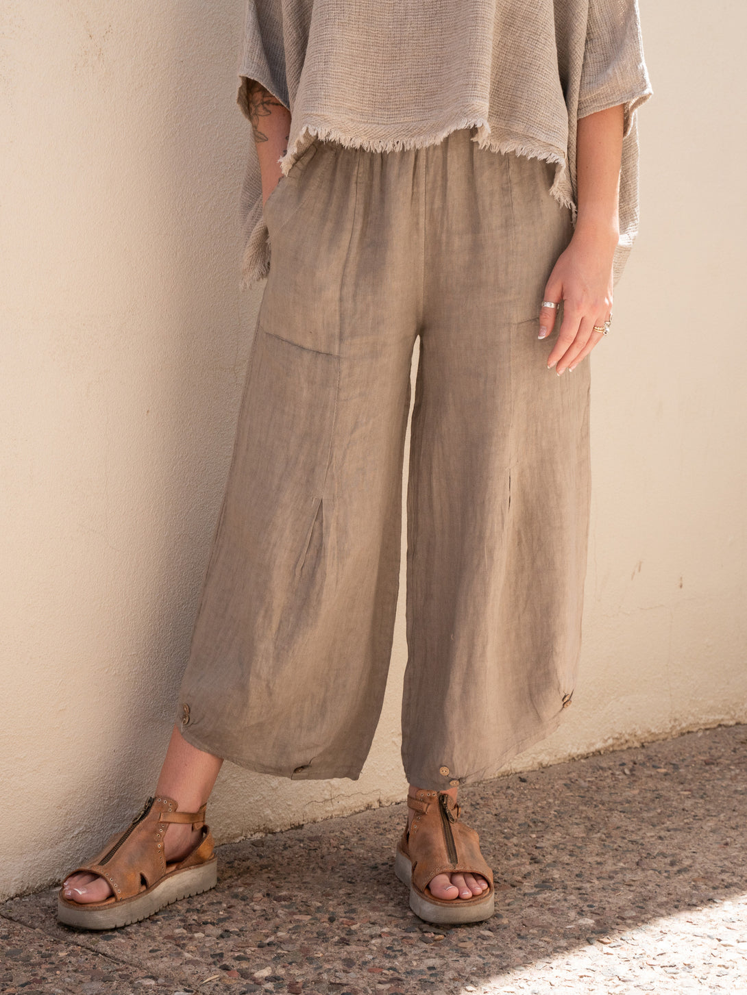 Conscious Coterie Yoli Linen Pant in Taupe on model pointing toe front view